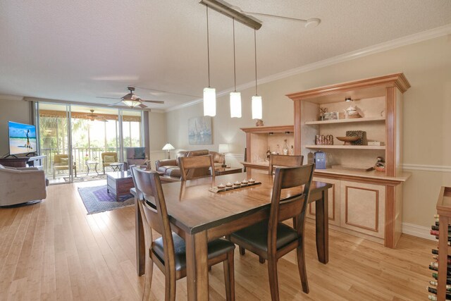 dining space with ceiling fan, a textured ceiling, light wood-type flooring, and crown molding