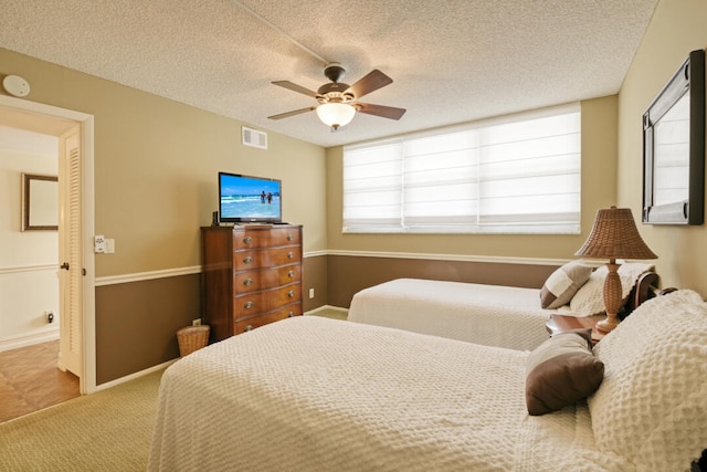 bedroom featuring carpet flooring, multiple windows, ceiling fan, and a textured ceiling