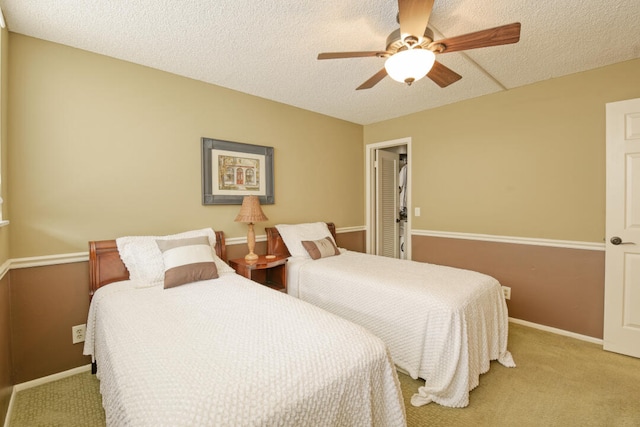 carpeted bedroom featuring ceiling fan and a textured ceiling