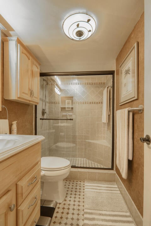 bathroom with walk in shower, vanity, and toilet