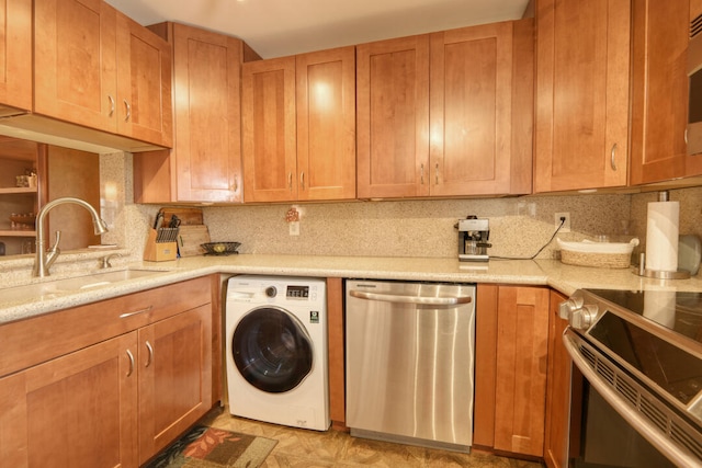 kitchen with washer / clothes dryer, light stone counters, tasteful backsplash, stainless steel appliances, and sink