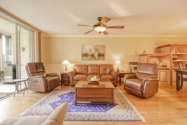 living room with a textured ceiling, ornamental molding, ceiling fan, and light hardwood / wood-style flooring