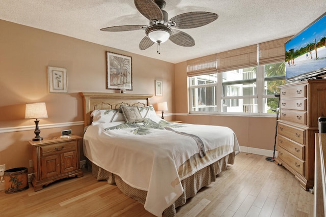 bedroom featuring light hardwood / wood-style floors, ceiling fan, and a textured ceiling