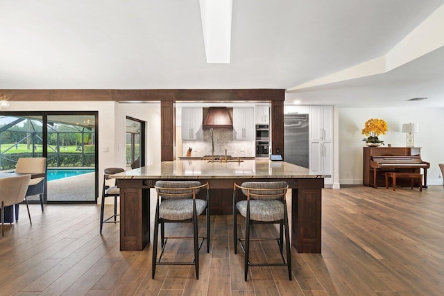 kitchen featuring dark hardwood / wood-style floors, a kitchen island, appliances with stainless steel finishes, a breakfast bar area, and light stone countertops