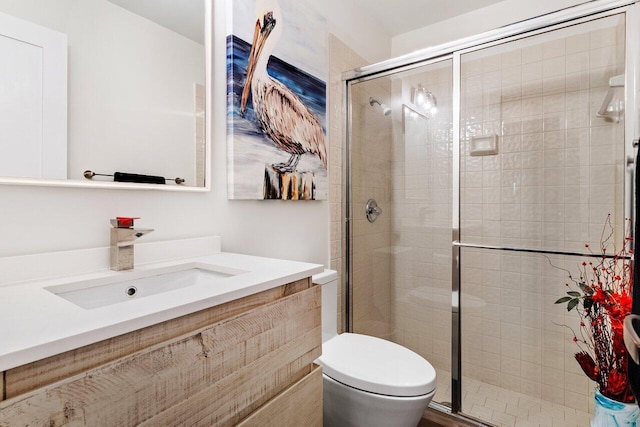 bathroom featuring toilet, a shower with door, and vanity