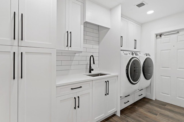 laundry area featuring washer and clothes dryer, cabinets, dark wood-type flooring, and sink