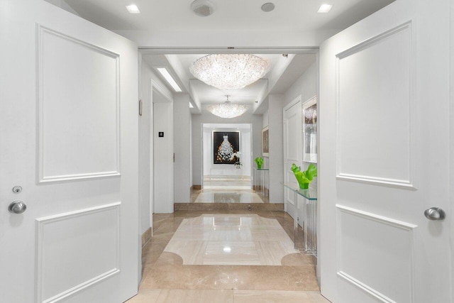 hallway featuring a chandelier and light tile patterned flooring