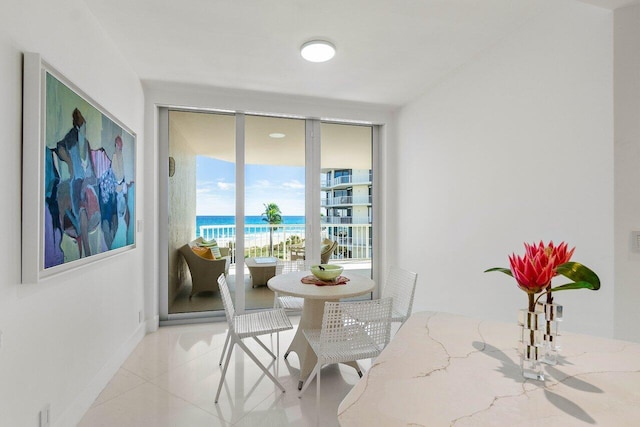 dining space with light tile patterned flooring, a water view, and a view of the beach