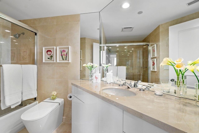 bathroom with tile patterned floors, vanity, toilet, and tile walls