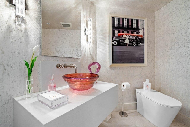 bathroom featuring tile patterned flooring, a textured ceiling, toilet, and sink