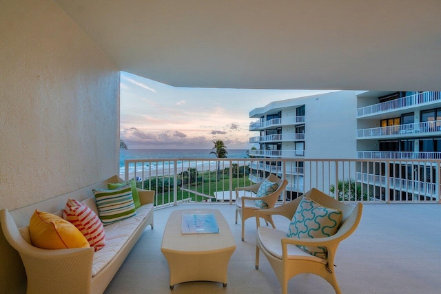 balcony at dusk featuring a water view