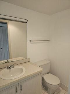 bathroom with toilet, vanity, and tile patterned floors