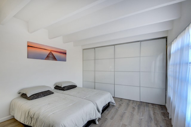 bedroom featuring light hardwood / wood-style flooring and beam ceiling