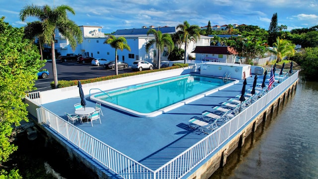 view of pool with a water view and a patio