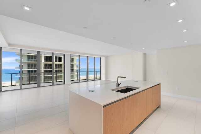 kitchen featuring modern cabinets, open floor plan, a water view, a large island with sink, and a sink