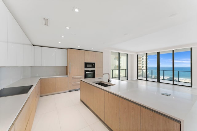 kitchen with light countertops, a water view, white cabinetry, modern cabinets, and black appliances