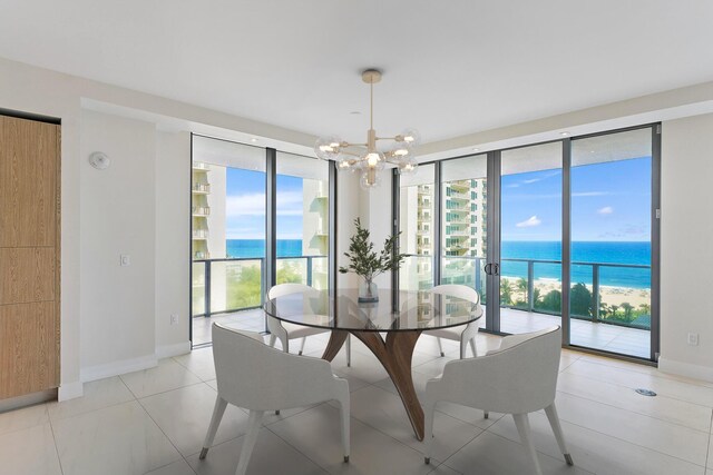 dining area featuring a notable chandelier, light tile patterned flooring, a water view, and expansive windows