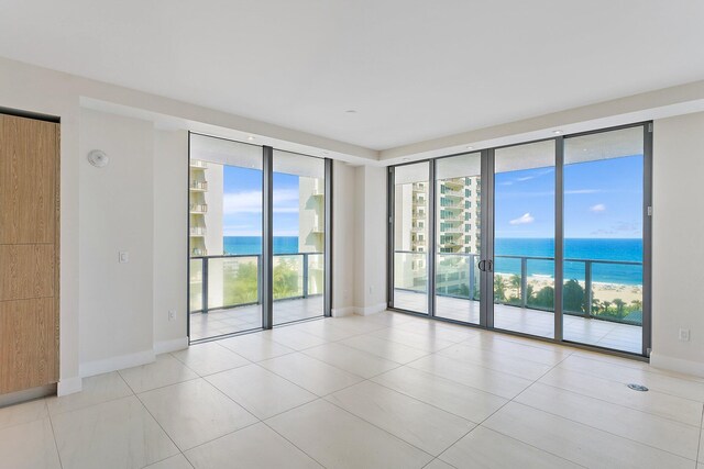 spare room with a water view, light tile patterned floors, and floor to ceiling windows