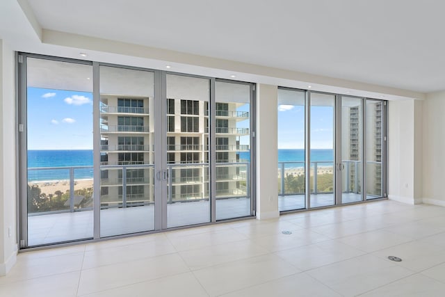 tiled empty room featuring expansive windows, a water view, and french doors