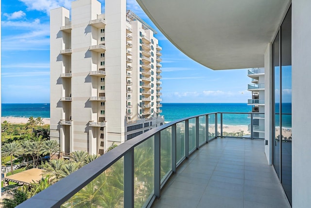 balcony with a water view and a view of the beach