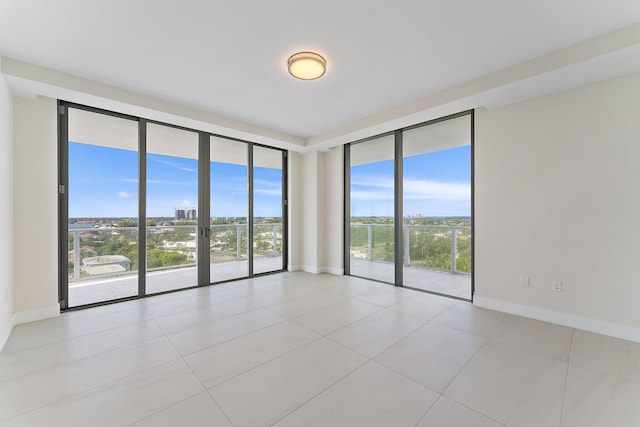 empty room featuring expansive windows, plenty of natural light, and baseboards