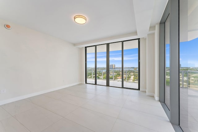 empty room with expansive windows, baseboards, and light tile patterned floors