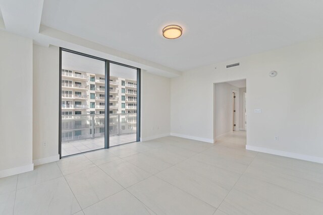 spare room with a wall of windows, a healthy amount of sunlight, and light tile patterned floors