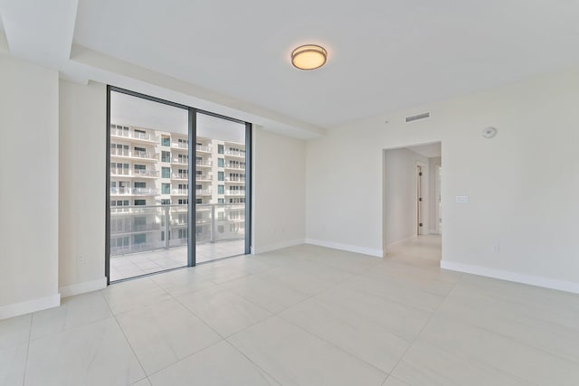 spare room featuring light tile patterned floors, visible vents, and baseboards