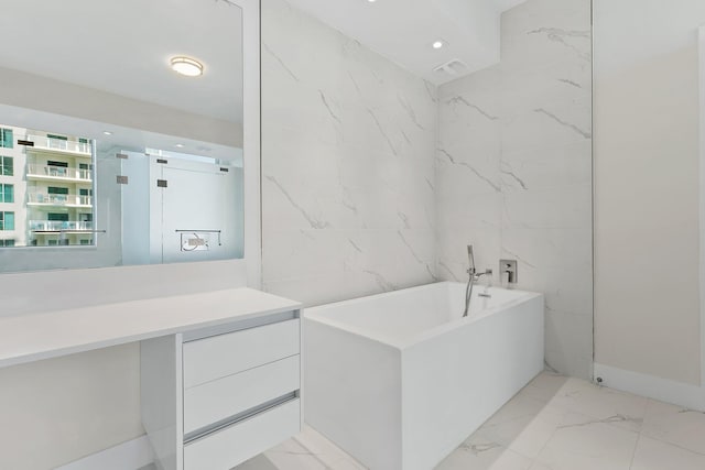 bathroom with marble finish floor, tile walls, recessed lighting, a soaking tub, and vanity