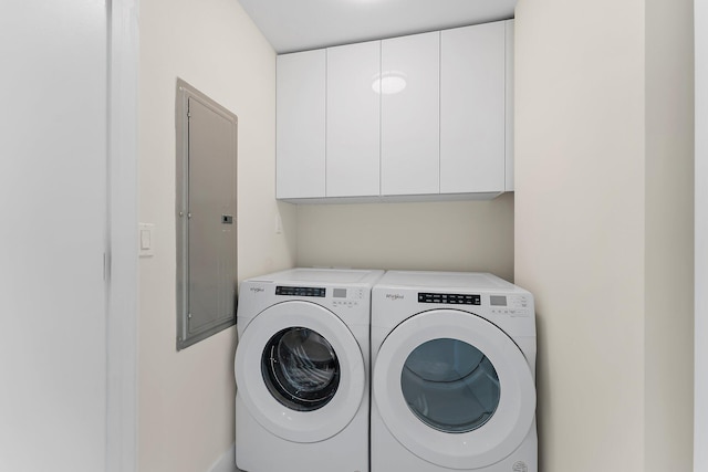 washroom with washer and clothes dryer, cabinet space, and electric panel