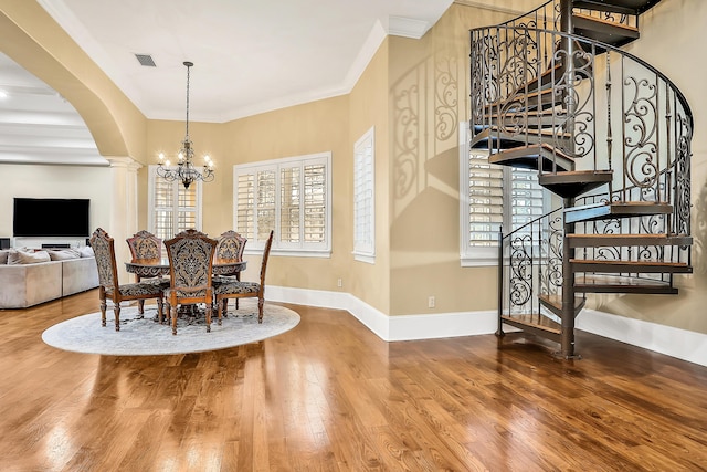 dining area with decorative columns, wood-type flooring, ornamental molding, and a chandelier