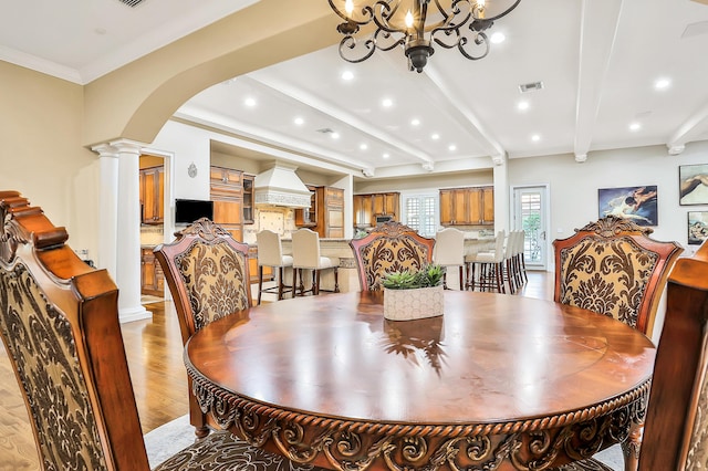 dining space with beam ceiling, ornamental molding, a chandelier, and light wood-type flooring