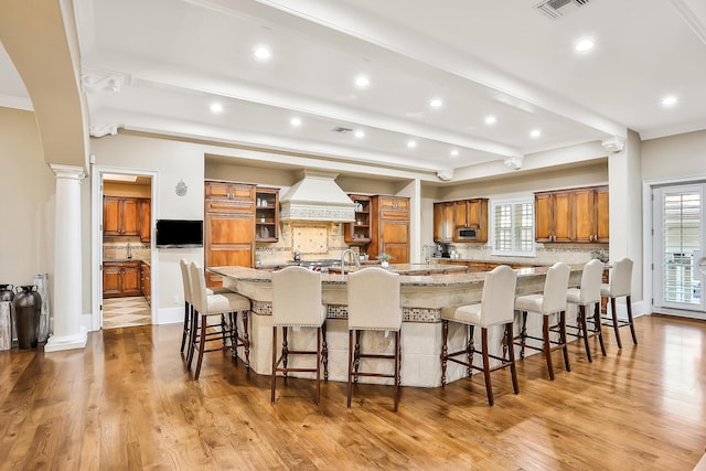 kitchen with a large island, decorative backsplash, premium range hood, and a wealth of natural light