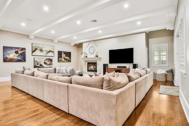 living room featuring beamed ceiling and light hardwood / wood-style floors