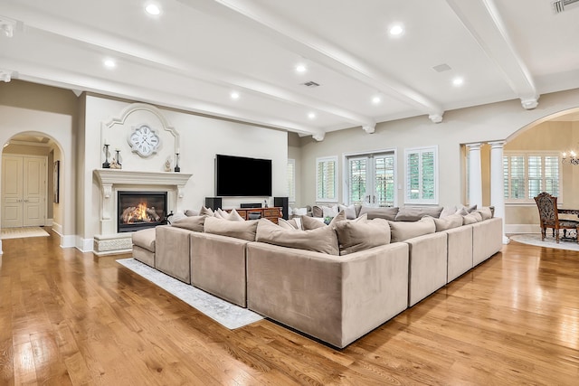 living room featuring a notable chandelier, beam ceiling, and light wood-type flooring