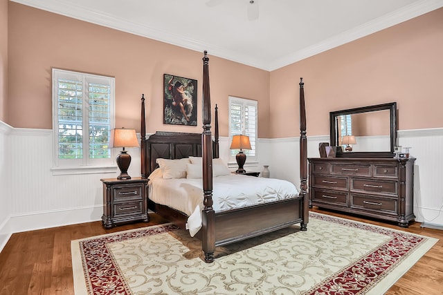 bedroom featuring hardwood / wood-style floors, ceiling fan, ornamental molding, and multiple windows