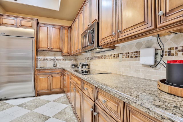 kitchen with decorative backsplash, light stone counters, sink, and appliances with stainless steel finishes