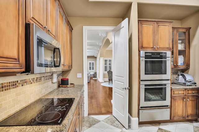 kitchen featuring backsplash, light hardwood / wood-style floors, light stone countertops, and stainless steel appliances