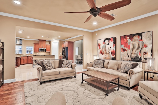 living room with ceiling fan, sink, light hardwood / wood-style floors, and ornamental molding