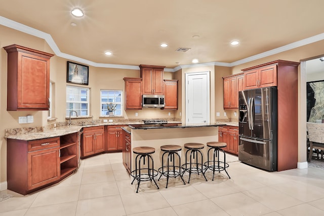 kitchen with a kitchen breakfast bar, a center island, stainless steel appliances, and ornamental molding