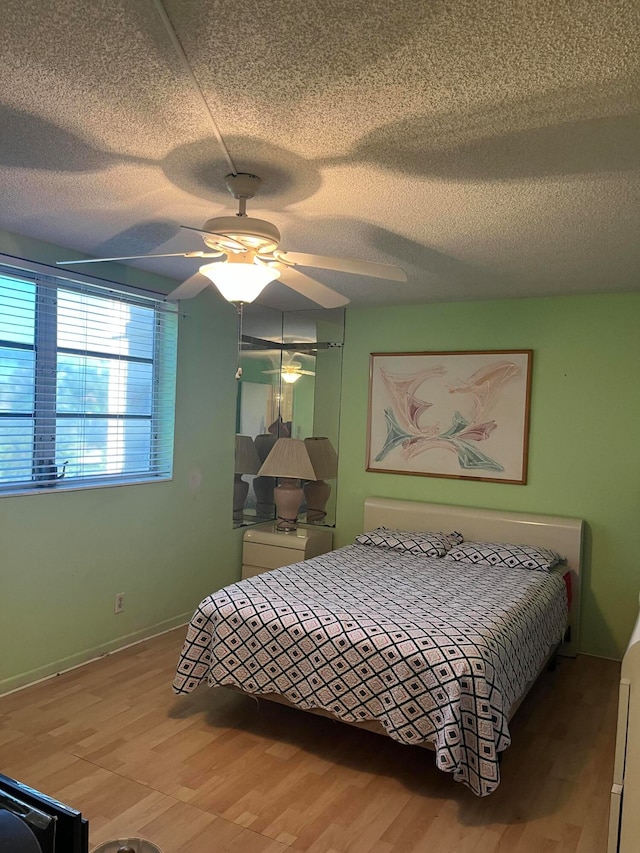 bedroom with a textured ceiling, ceiling fan, and hardwood / wood-style floors