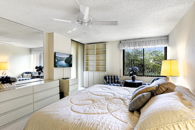 bedroom featuring a textured ceiling, light colored carpet, and ceiling fan