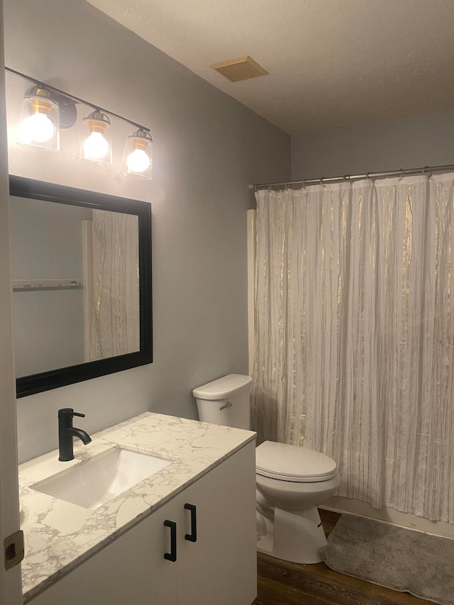 bathroom featuring hardwood / wood-style floors, vanity, a shower with curtain, toilet, and a textured ceiling