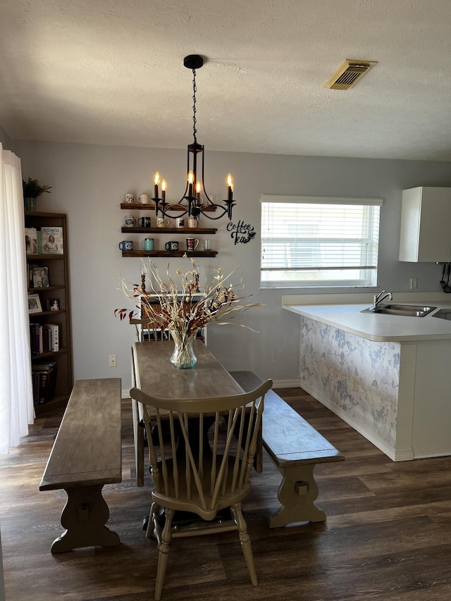 dining room featuring a textured ceiling, dark hardwood / wood-style flooring, sink, and an inviting chandelier