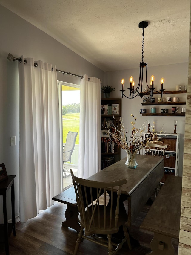 dining space with a textured ceiling, dark hardwood / wood-style floors, a chandelier, and vaulted ceiling