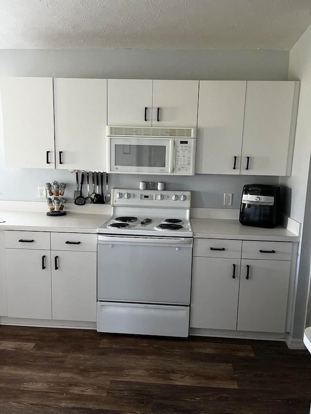 kitchen with white cabinets, dark hardwood / wood-style floors, and white appliances