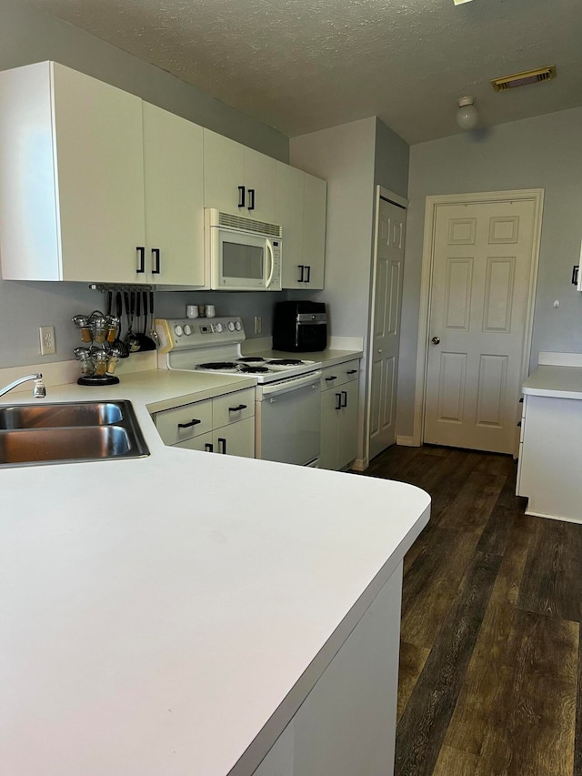 kitchen with sink, dark wood-type flooring, kitchen peninsula, a textured ceiling, and white appliances