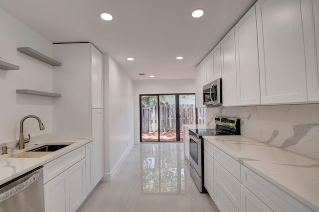 kitchen with light stone countertops, appliances with stainless steel finishes, white cabinetry, and sink