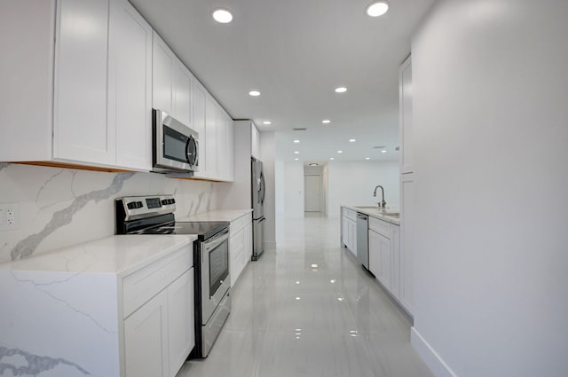 kitchen featuring decorative backsplash, light stone counters, stainless steel appliances, sink, and white cabinets