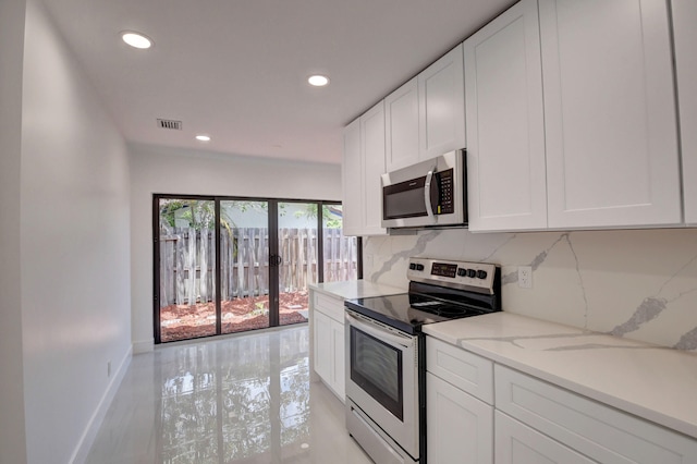 kitchen featuring white cabinets, backsplash, light stone countertops, and stainless steel appliances